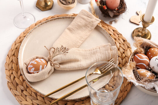 Beautiful table setting for Easter celebration with painted eggs on white background