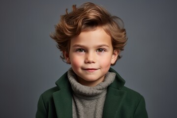 Portrait of a cute little boy in a green coat and scarf.