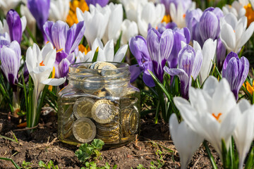 Glass jar with Kazakhstan coins in denominations of 100 and 200 tenge against a background of...