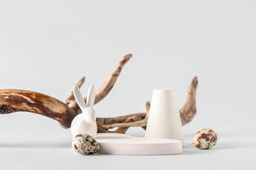 Decorative podiums with Easter eggs, toy bunny and branch on white background