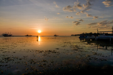 Golden Sunset Reflections. Tranquil beach scene with boats silhouetted against a colorful sky during sunset