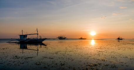 Golden Sunset Serenity. A tranquil beach scene at dusk with boats silhouetted against the horizon. Nature&rsquo;s beauty in perfect harmony.