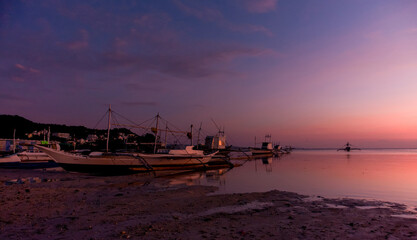 Golden Sunset Reflections. Tranquil beach scene with boats silhouetted against a colorful sky during sunset