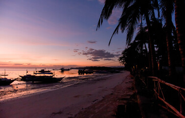 Golden Sunset Reflections. Tranquil beach scene with boats silhouetted against a colorful sky during sunset