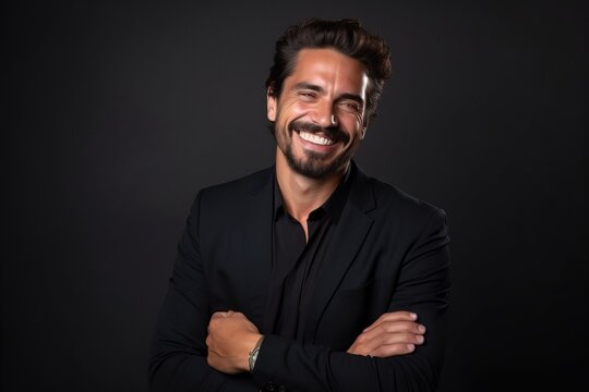 Portrait of a handsome young business man smiling on black background.
