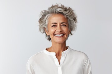 Beautiful senior woman looking at camera and smiling while standing against grey background