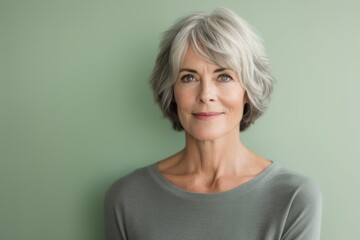 Portrait of a senior woman with grey hair against a green background