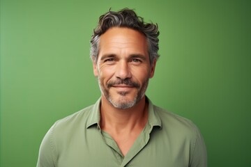 Portrait of a handsome middle-aged man smiling at the camera against green background - obrazy, fototapety, plakaty
