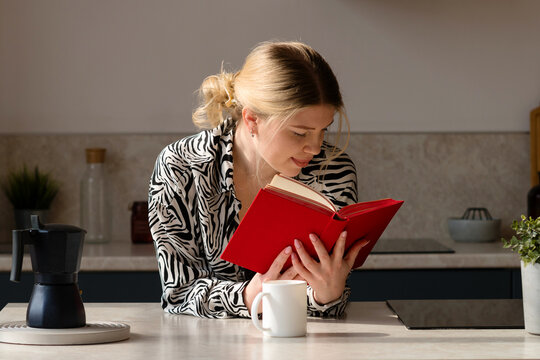 Woman reading book, enjoying coffee.
