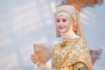 Beautiful bride in traditional Muslim wedding dress applied with luxurious Thai clothing combined blend of two cultures in the Lanna style, Chiang Mai, Thailand.