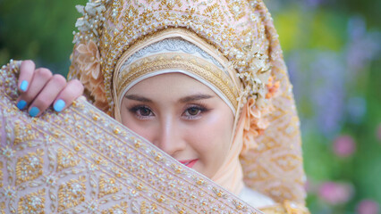 Beautiful bride in traditional Muslim wedding dress applied with luxurious Thai clothing combined...