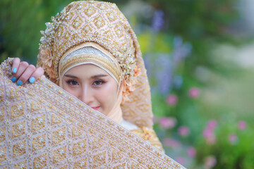 Beautiful bride in traditional Muslim wedding dress applied with luxurious Thai clothing combined...