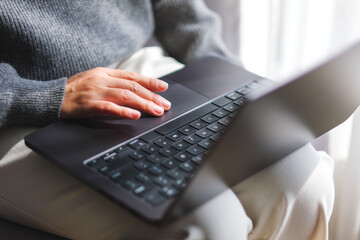 Closeup image of a woman working and touching on laptop computer touchpad at home