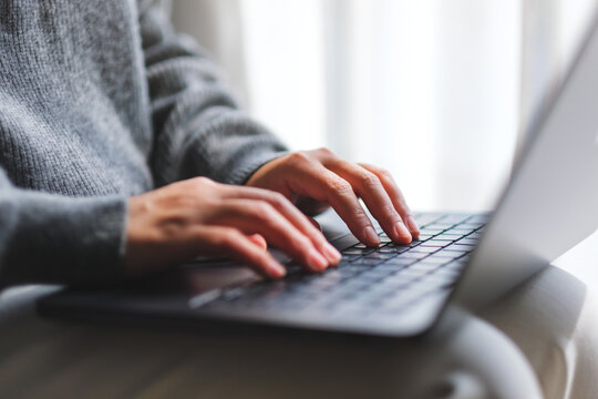 Closeup image of a woman typing on laptop computer at home