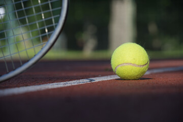Tennis racquet and yellow tennis ball near white line