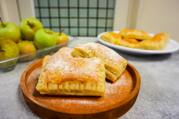 Homemade mini apple pie pastry placed on a plate with fresh apple in the background
