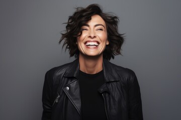 Cheerful woman in leather jacket looking at camera and laughing.
