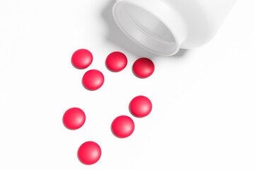 The remains of red oval pills are scattered next to the empty bottle.