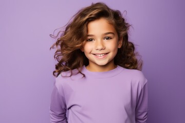 portrait of smiling little girl with long curly hair on violet background