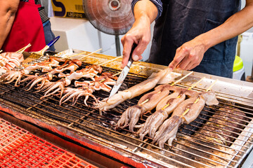 Close-up of the vendor is grilling squid skewers in the night market of Taiwan.