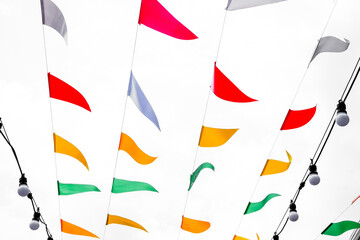 Colorful flags of different colors hanging in the wind on white background