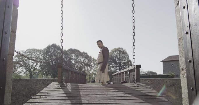 Cinematic shot of draw bridge lowering and knight entering castle