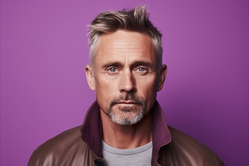 Handsome mature man in a brown leather jacket. Studio shot over purple background.