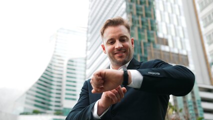 Low angle camera of businessman looking at watch to remind about time. Smart caucasian businessman...