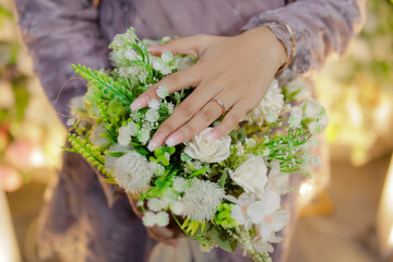 Woman's hand holding a bouquet of flowers and wearing a ring
