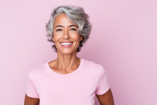 Beautiful mature woman looking at camera and smiling while standing against pink background