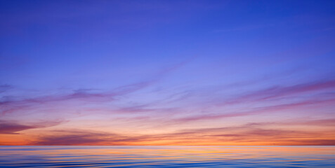 Idyllic sunset sky background over sea with colorful sunlight reflection on motion blur of flowing...