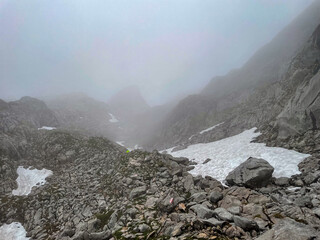 A hike though the Berchtesgaden landscape during summer with rain clouds and remaining snow fields