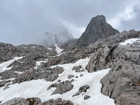 A hike though the Berchtesgaden landscape during summer with rain clouds and remaining snow fields