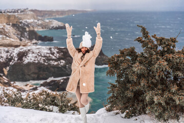 Woman snow sea. Amidst a wintry backdrop, a woman in a beige faux fur coat gleefully engages in a...