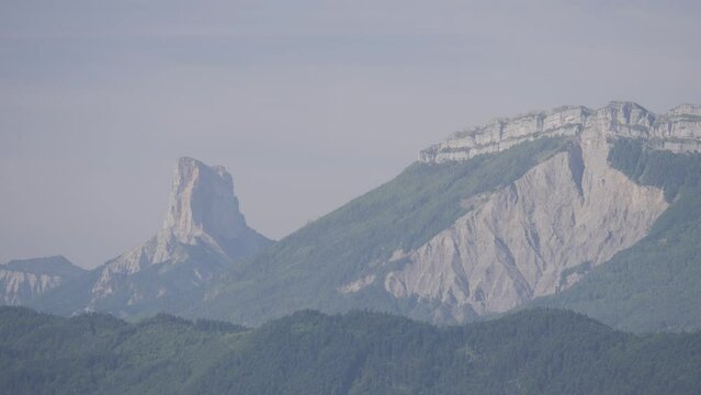 Shot of two mountains, with one covered in trees and the other one with a pointy peak