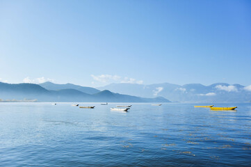 A group of small wooden fishing row boat on blue Lugu Lake. Lakeside blue water in the distance...