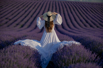 Back view woman lavender sunset. Happy woman in white dress holds lavender bouquet. Aromatherapy...