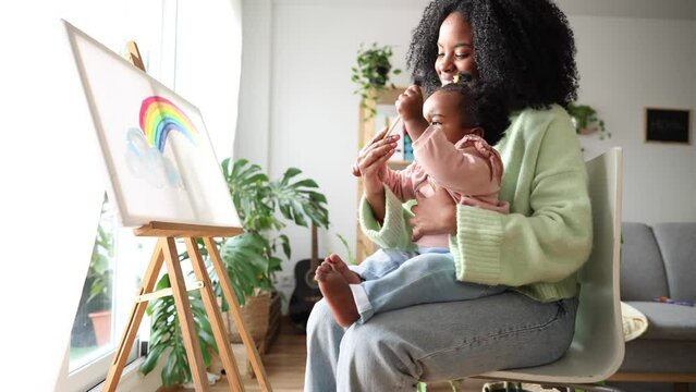 A mother guides her toddler in painting a colorful rainbow, sparking creativity and imagination. Creative Learning Time with Mother and Toddler