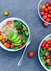 Three bowls of natural foods with avocado, tomatoes, spinach, and rice on table