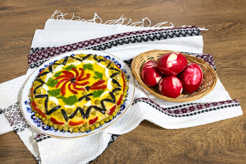 Traditional Romanian boeuf (beef) salad decorated and red Easter eggs with a traditional towel on a wooden table