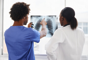 Doctor, nurse and review xray for healthcare, collaboration for surgery and treatment plan with cardiology. Black people study lung scan, MRI or radiology, medicine and surgeon with team at hospital - obrazy, fototapety, plakaty