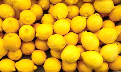 Colorful Display Of Lemons at fruit and vegetables street Market, organic ecological food from local producers. Ripe Yellow Lemons Close-up Background Or Texture. Lemon Harvest, Many Yellow Lemons.