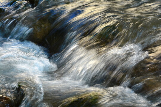 Long exposure smooth flow of water streaming fast In daylight. Abstract landscape