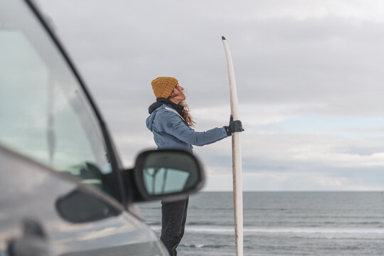 Woman standing next to surf board winter iceland
