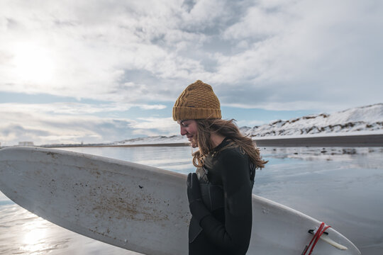 Woman walking on beach with surf board winter iceland