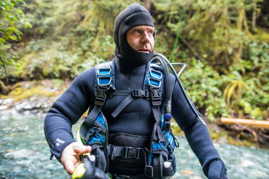 Portrait of diver wearing wetsuit and BCD, holding air gauge