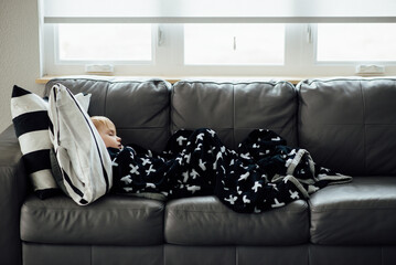 Side profile of young boy sleeping on couch in daytime.