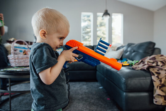 Profile of toddler aiming toy gun in living room