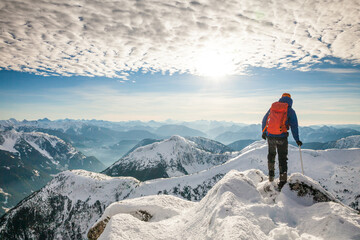 Rear view of mountaineer standing on snow covered summit
