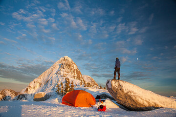 Mountaineer and basecamp on summit ridge at sunset